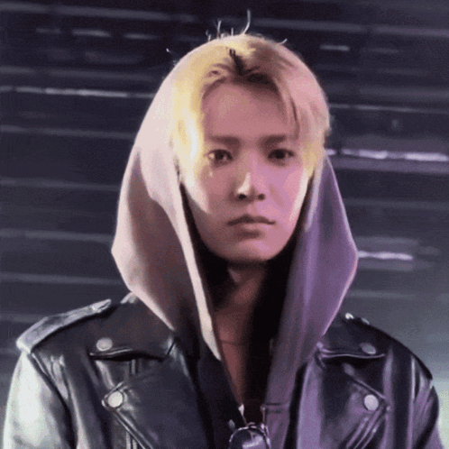 A Young Man Wearing A Hoodie And A Leather Jacket Looks At The Camera GIF