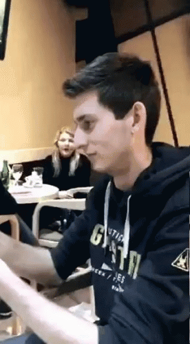 A Young Man Wearing A Hoodie That Says Gsta Is Sitting At A Table GIF