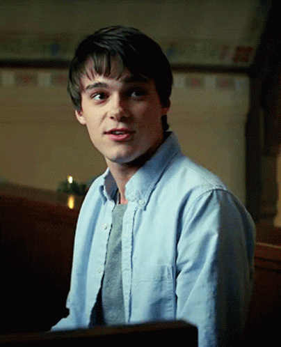 A Young Man Wearing A Light Blue Shirt And A Grey Sweater GIF