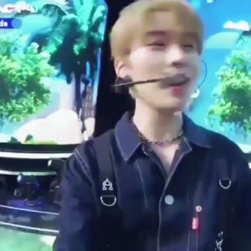 A Young Man Wearing A Microphone And A Necklace Is Sitting In Front Of A Tv . GIF