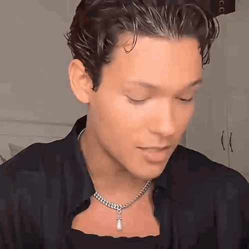 A Young Man Wearing A Necklace With A Pearl Pendant On His Neck . GIF