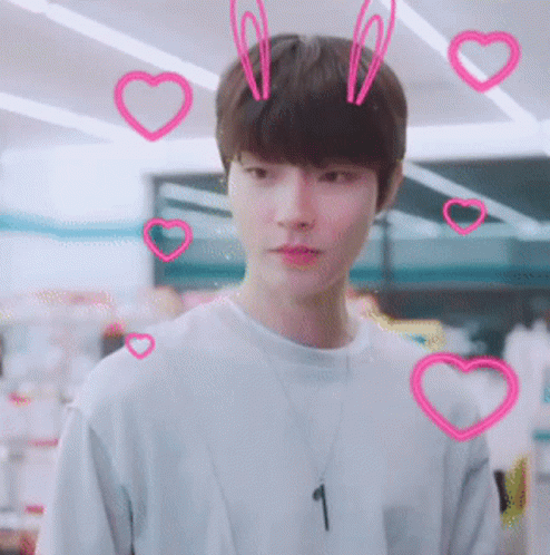 A Young Man Wearing A Necklace With The Number 1 On It Surrounded By Pink Hearts GIF