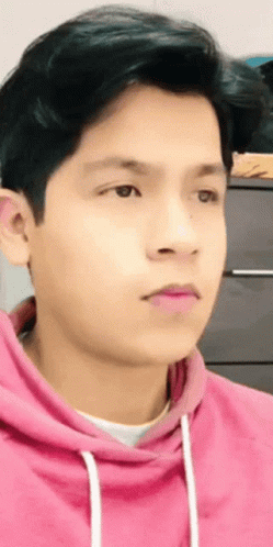 A Young Man Wearing A Pink Hoodie Looks To The Side GIF