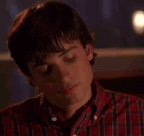 A Young Man Wearing A Plaid Shirt Is Looking At The Camera . GIF