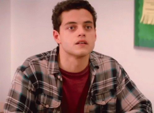 A Young Man Wearing A Plaid Shirt Looks Surprised GIF