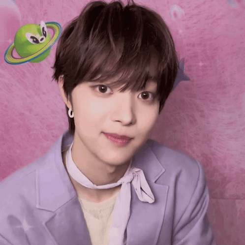A Young Man Wearing A Purple Jacket And A White Scarf Looks At The Camera In Front Of A Pink Background GIF
