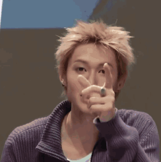 A Young Man Wearing A Purple Sweater Is Touching His Forehead GIF