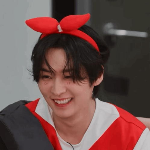 A Young Man Wearing A Red Bow On His Head Smiles GIF