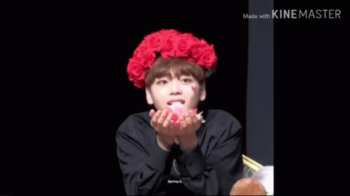 A Young Man Wearing A Red Flower Crown Is Blowing Petals In The Air . GIF