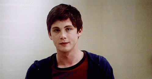 A Young Man Wearing A Red Shirt And A Blue Hoodie Is Standing In Front Of A White Wall . GIF