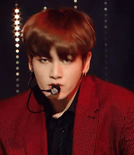 A Young Man Wearing A Red Suit And A Microphone In His Mouth GIF