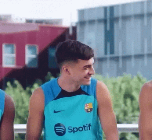 A Young Man Wearing A Spotify Shirt Is Smiling While Standing Next To A Group Of Young Men . GIF