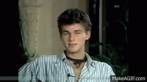 A Young Man Wearing A Striped Shirt And A Choker Is Sitting In A Chair With His Eyes Closed . GIF