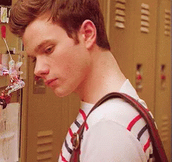 A Young Man Wearing A Striped Shirt And Carrying A Purse GIF