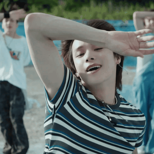 A Young Man Wearing A Striped Shirt Is Smiling GIF