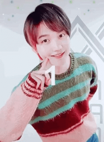 A Young Man Wearing A Striped Sweater Is Making A Heart Shape With His Hand . GIF