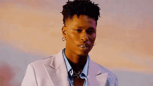 A Young Man Wearing A Suit And Earrings Is Looking At The Camera With His Mouth Open . GIF