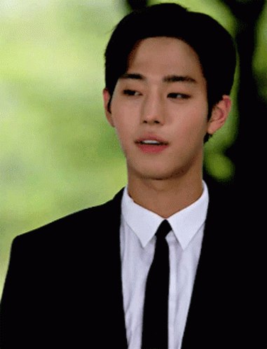 A Young Man Wearing A Suit And Tie Looks To His Left GIF