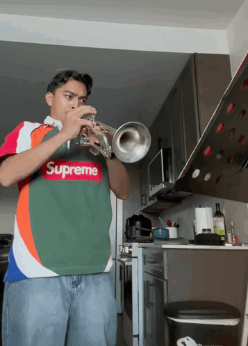 A Young Man Wearing A Supreme Shirt Plays A Trumpet GIF