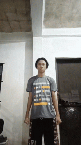 A Young Man Wearing A T-Shirt That Says ' Happiness ' On It Stands In A Room GIF