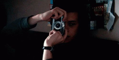 A Young Man Wearing A Watch Is Playing A Video Game In A Dark Room . GIF