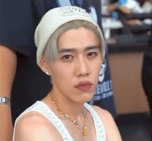 A Young Man Wearing A White Beanie And A White Tank Top . GIF