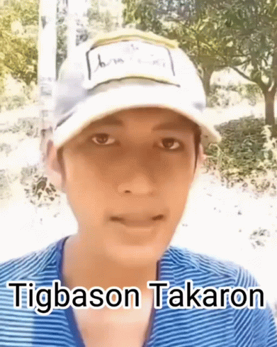 A Young Man Wearing A White Hat And A Blue Shirt Is Talking . GIF