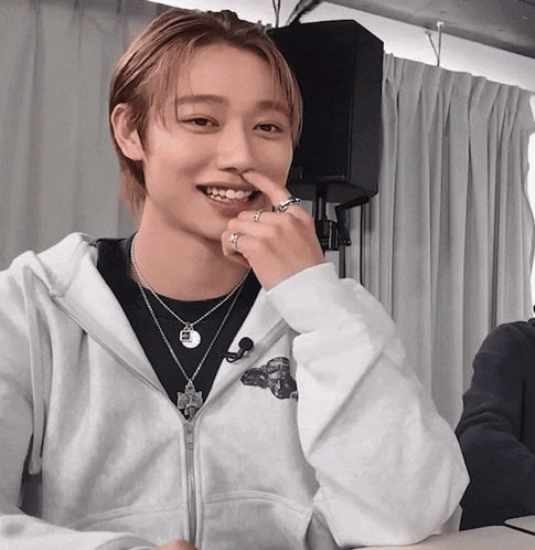 A Young Man Wearing A White Hoodie And A Necklace With The Letter R On It GIF