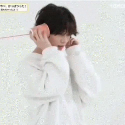 a young man wearing a white hoodie is talking on a cell phone .