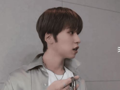 A Young Man Wearing A White Shirt And A Necklace Looks To The Side GIF