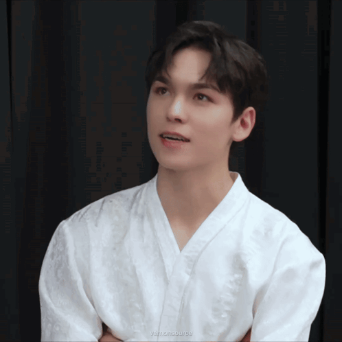 A Young Man Wearing A White Shirt With A Black Curtain Behind Him And The Words Yemonisource On The Bottom Left GIF