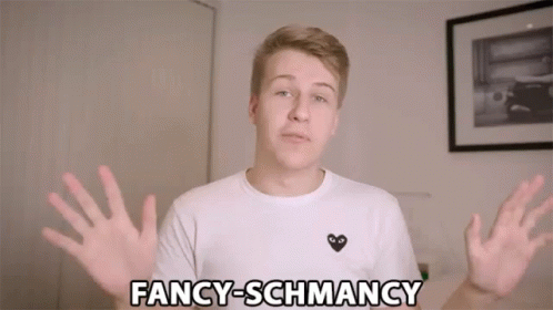 A Young Man Wearing A White Shirt With A Black Heart On It Says Fancy-Schmancy GIF