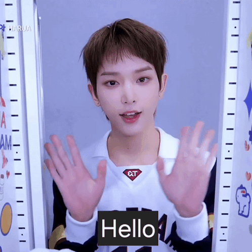 A Young Man Wearing A White Shirt With The Word Qt On It Says Hello GIF