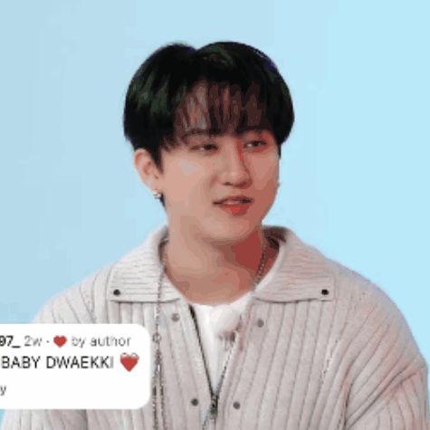 A Young Man Wearing A White Sweater And A Necklace Has A Sticker On His Neck That Says Baby Dwaekki GIF