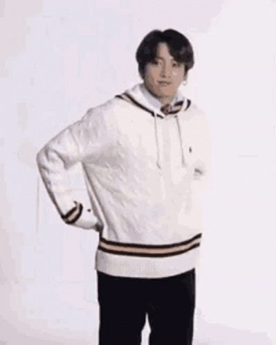 A Young Man Wearing A White Sweater And Black Pants Is Standing On One Leg . GIF