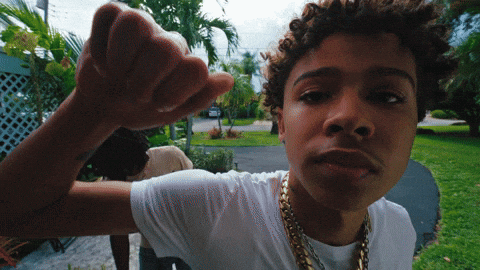 A Young Man Wearing A White T-Shirt And Gold Chains Is Making A Fist GIF