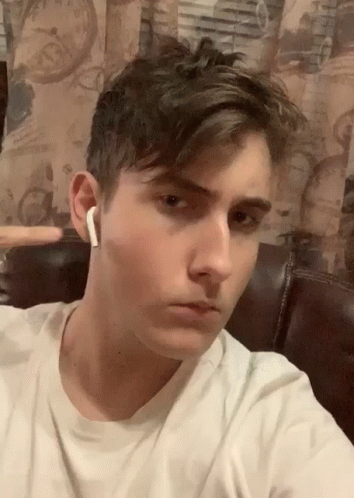 A Young Man Wearing A White T-Shirt And White Earbuds Takes A Selfie GIF