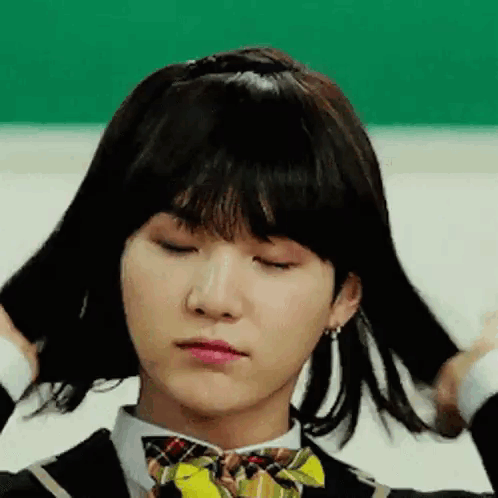 A Young Man Wearing A Wig And A Bow Tie Is Making A Funny Face . GIF