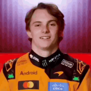 A Young Man Wearing A Yellow And Black Racing Jacket With The Word Android On It . GIF