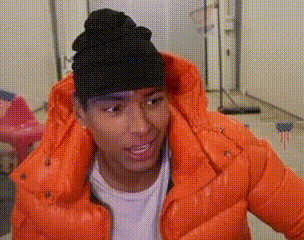 A Young Man Wearing An Orange Jacket And A Black Beanie . GIF