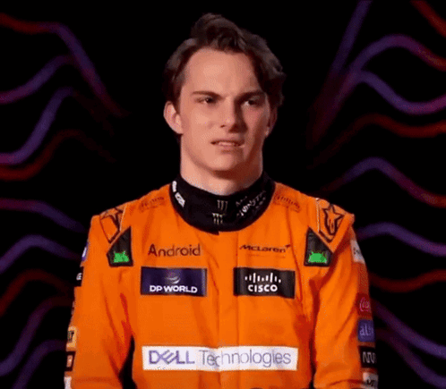 A Young Man Wearing An Orange Racing Suit With Dell Technologies Written On It GIF