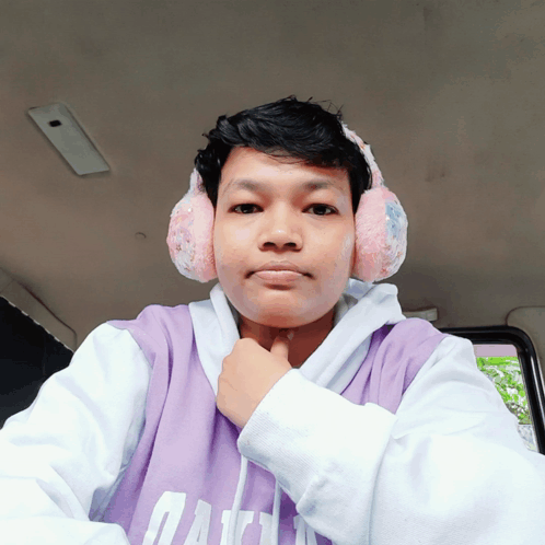 A Young Man Wearing Ear Muffs And A Purple Shirt That Says Gap On It GIF