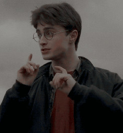 A Young Man Wearing Glasses And A Black Jacket Is Pointing His Finger Up . GIF