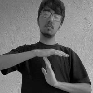 A Young Man Wearing Glasses And A Black Shirt Is Making A Gesture With His Hands . GIF
