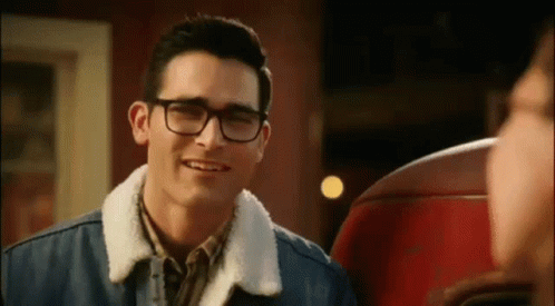 A Young Man Wearing Glasses And A Denim Jacket Is Smiling . GIF