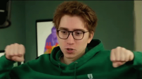 A Young Man Wearing Glasses And A Green Hoodie Is Giving A Thumbs Down Sign . GIF