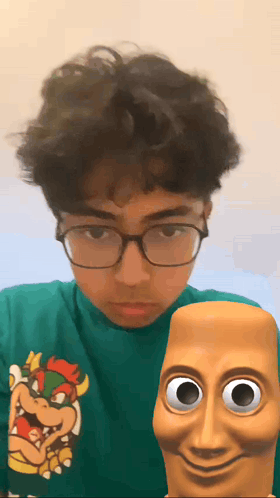 A Young Man Wearing Glasses And A Green Shirt With A Bowser On It GIF