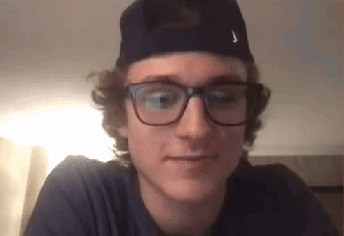 A Young Man Wearing Glasses And A Hat Has The Letter J On His Hat GIF