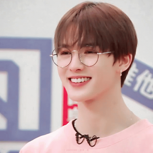 A Young Man Wearing Glasses And A Pink Shirt Smiles At The Camera GIF