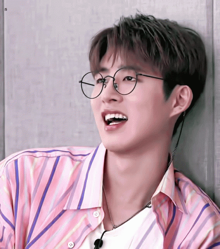 A Young Man Wearing Glasses And A Pink Striped Shirt Is Smiling GIF